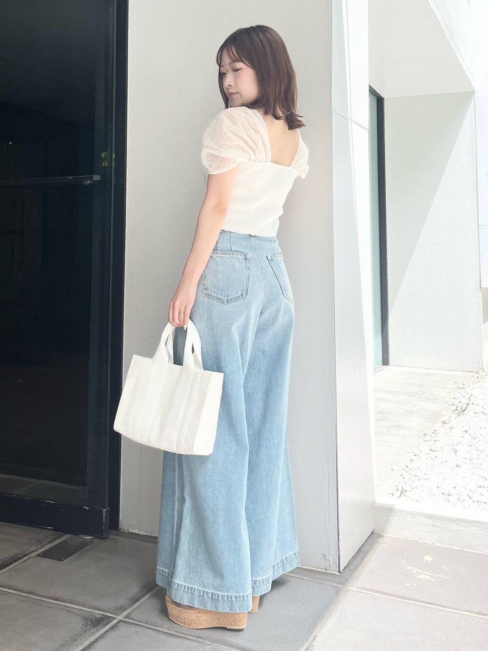 ホワイト系のニット/セーター、ブルー系のデニムパンツ、ホワイト系のトートバッグを着用したレディースの夏コーディネートの2枚目の写真