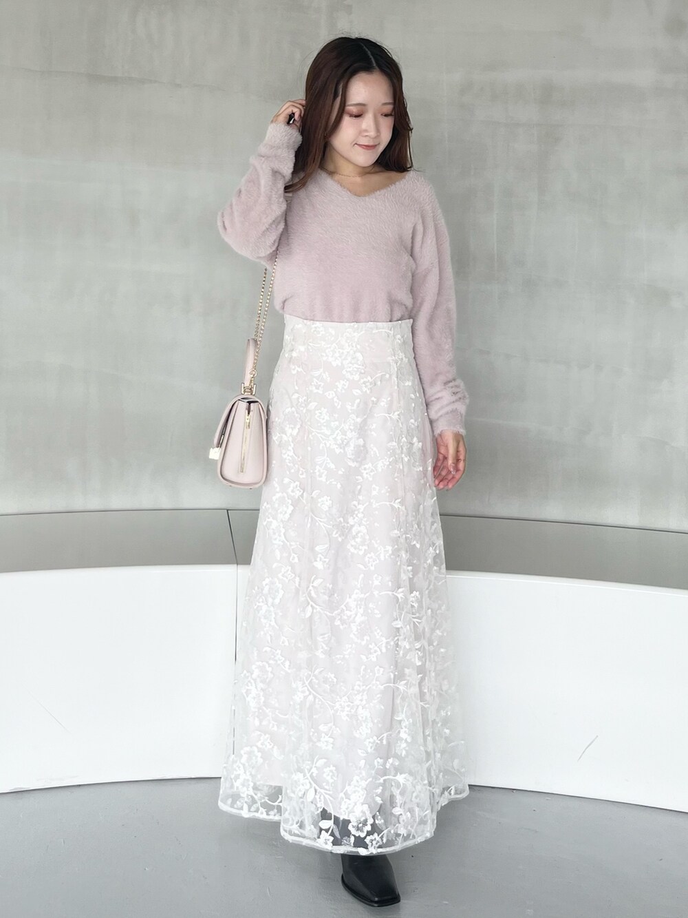 ホワイト系のスカート、ピンク系のニット/セーター、ピンク系のショルダーバッグを着用したレディースの秋コーディネートの2枚目の写真