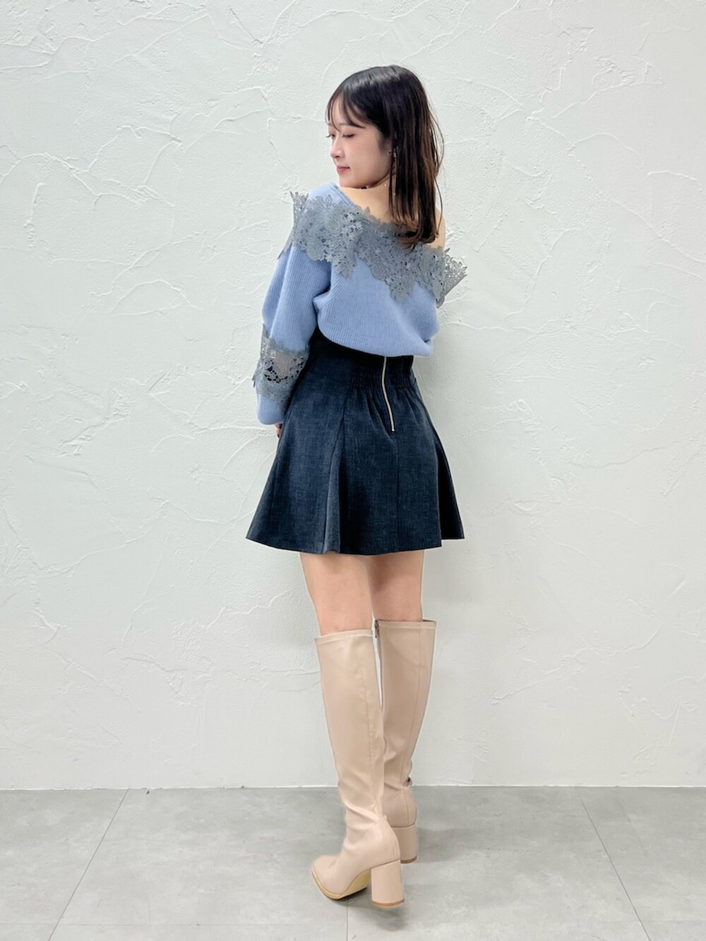 ベージュ系のブーツ、ブラック系のダウンジャケット/コート、ブルー系のニット/セーターを着用したレディースの秋コーディネートの3枚目の写真