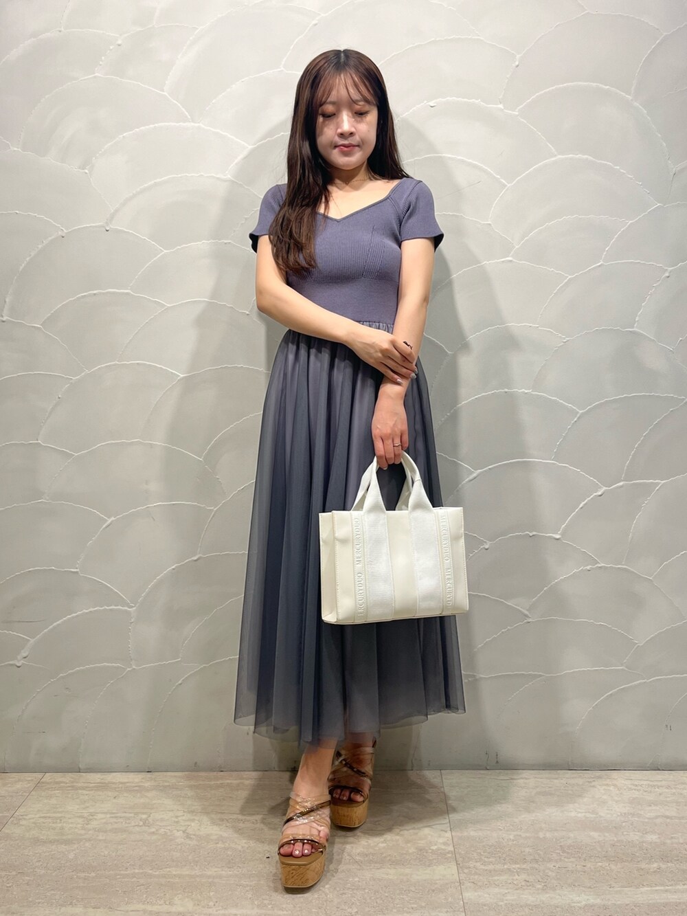 グレー系のワンピース、ホワイト系のトートバッグ、ホワイト系のカーディガン/ボレロを着用したレディースの春コーディネートの2枚目の写真