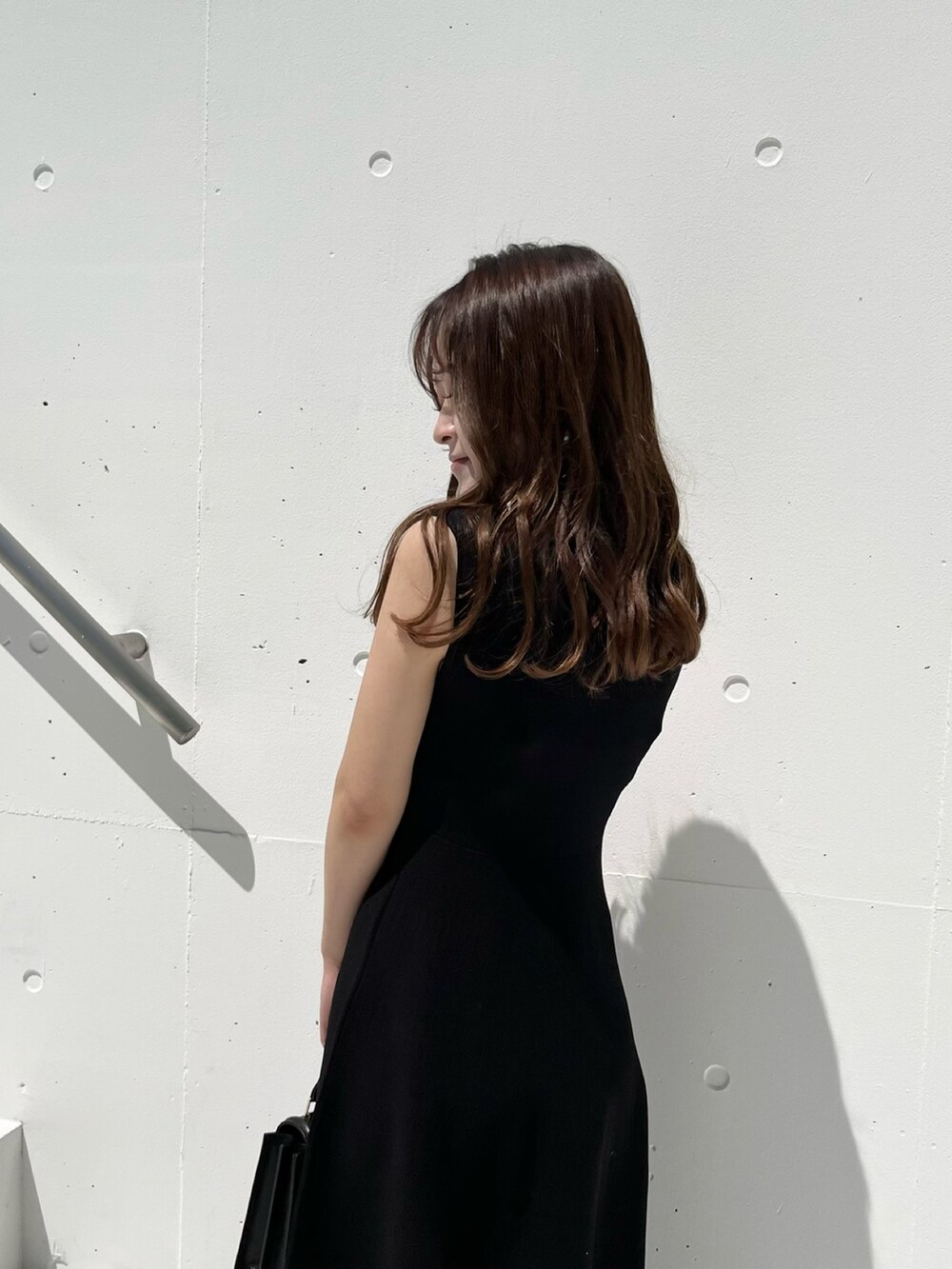 ブラック系のワンピース、ブラウン系のサンダル、ブラック系のハンドバッグを着用したレディースの春コーディネートの4枚目の写真