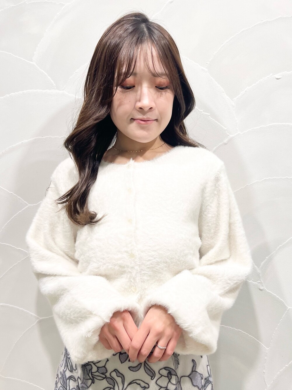 ホワイト系のカーディガン/ボレロ、グレー系のスカート、ブラック系のブーツを着用したレディースの冬コーディネートの5枚目の写真