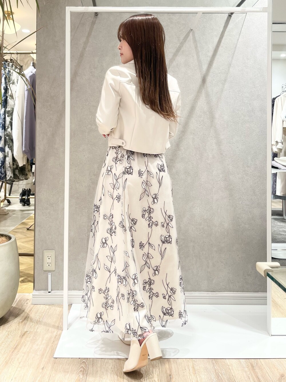 ベージュ系のワンピース、ホワイト系のライダースジャケット、ホワイト系のブーツを着用したレディースの春コーディネートの3枚目の写真