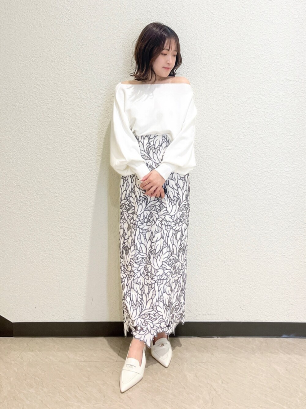 イエロー系のトレンチコート、ホワイト系のニット/セーター、ホワイト系のスカートを着用したレディースの冬コーディネートの4枚目の写真