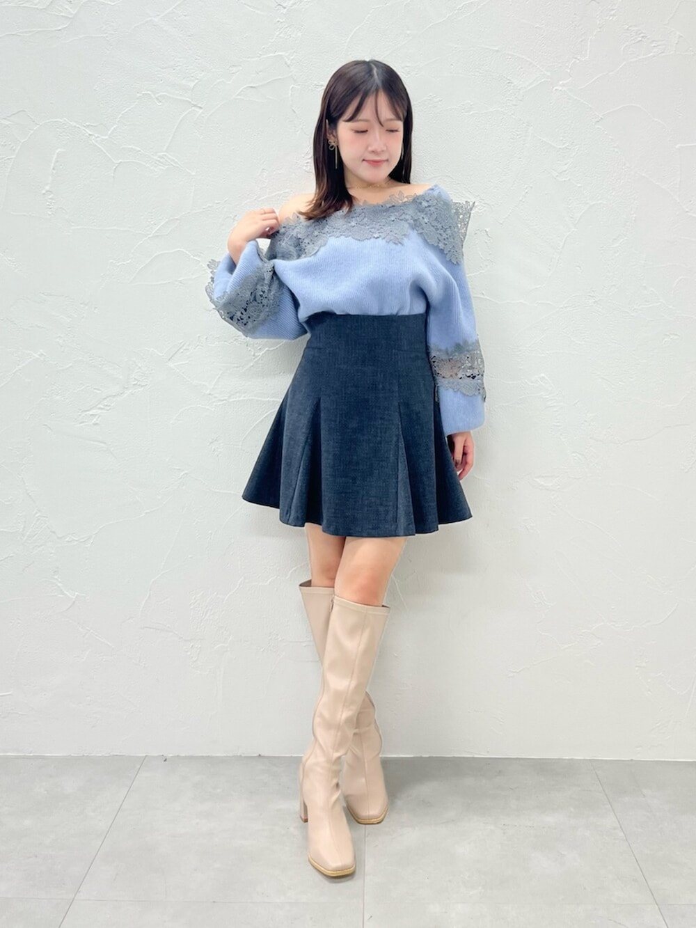 ベージュ系のブーツ、ブラック系のダウンジャケット/コート、ブルー系のニット/セーターを着用したレディースの秋コーディネートの2枚目の写真