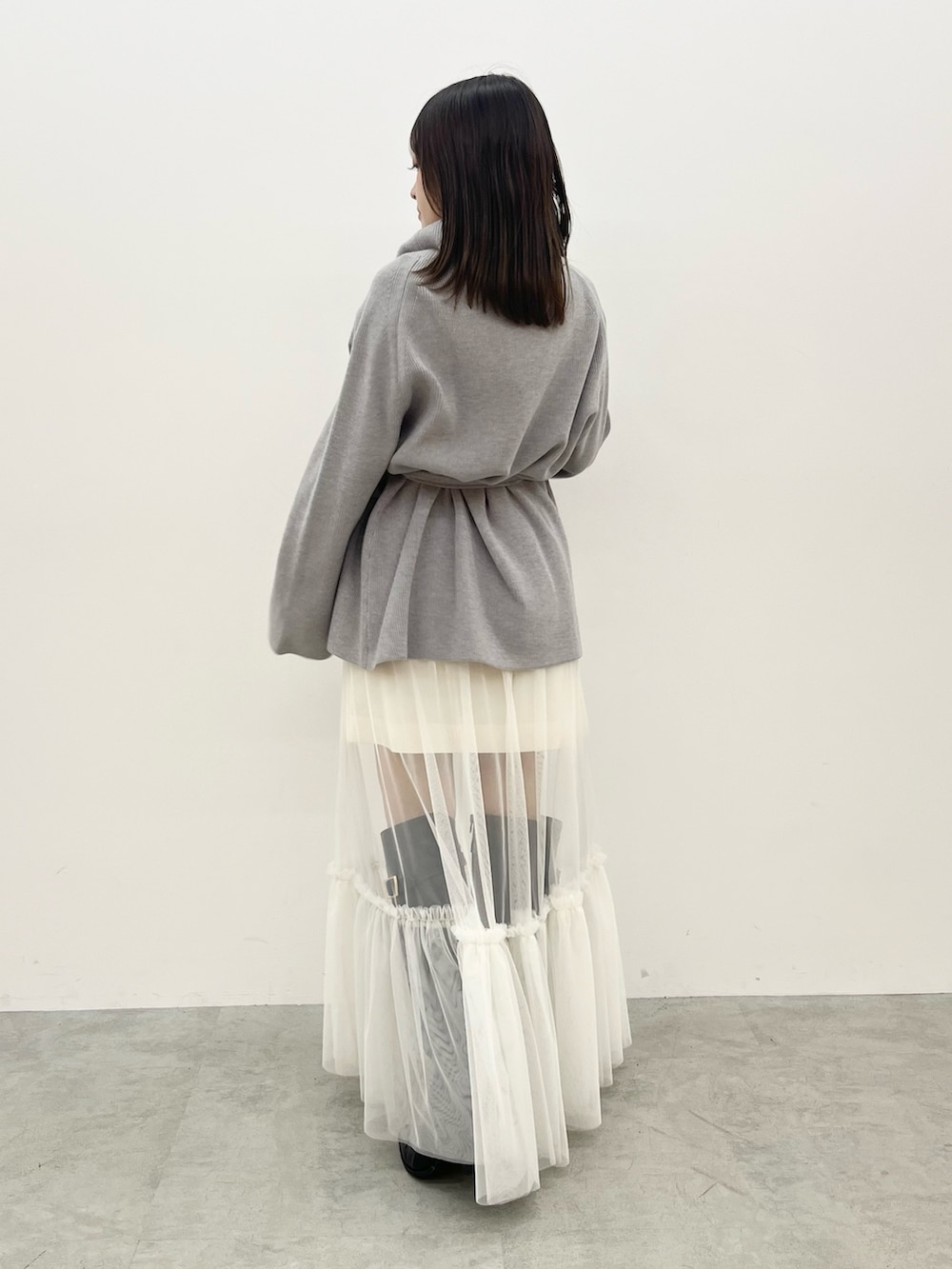 グレー系のニット/セーター、ホワイト系のスカートを着用したレディースの夏コーディネートの3枚目の写真