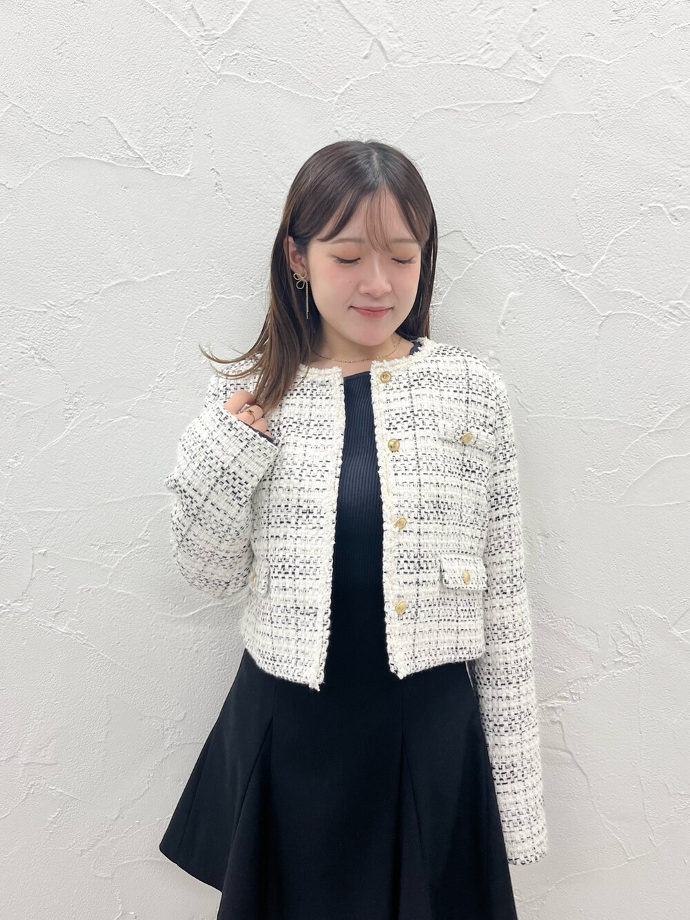 ホワイト系のノーカラージャケット、ブラック系のスカート、ブラック系のブーツを着用したレディースの秋コーディネートの5枚目の写真