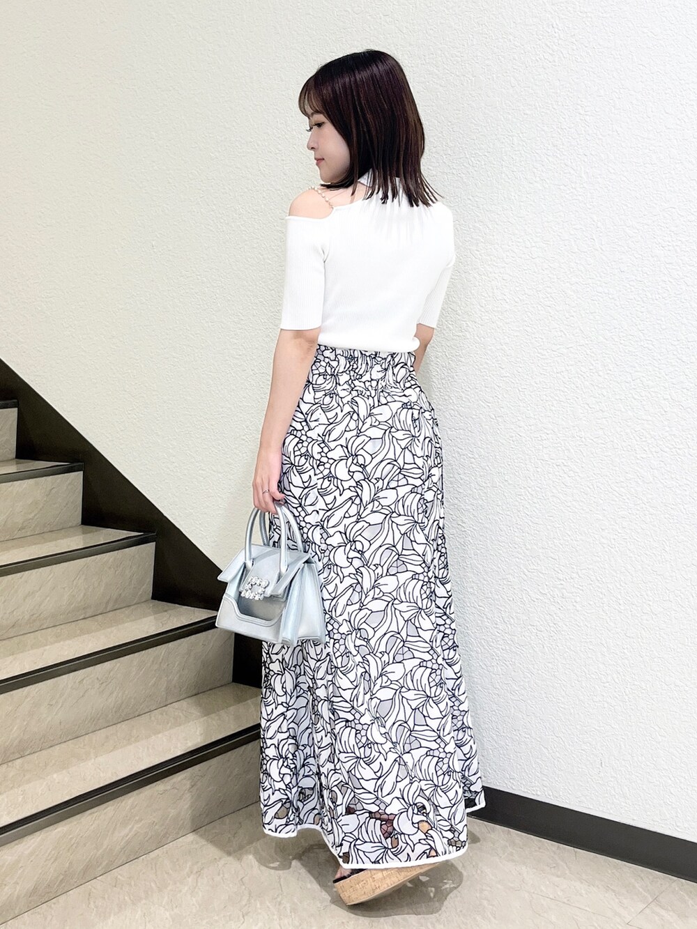 ホワイト系のスカート、ホワイト系のニット/セーター、シルバー系のショルダーバッグを着用したレディースの夏コーディネートの3枚目の写真