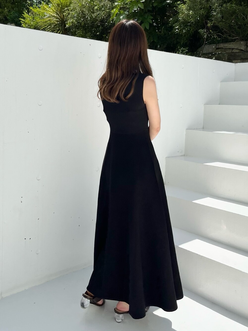 ブラック系のワンピース、ブラウン系のサンダル、ブラック系のハンドバッグを着用したレディースの春コーディネートの6枚目の写真