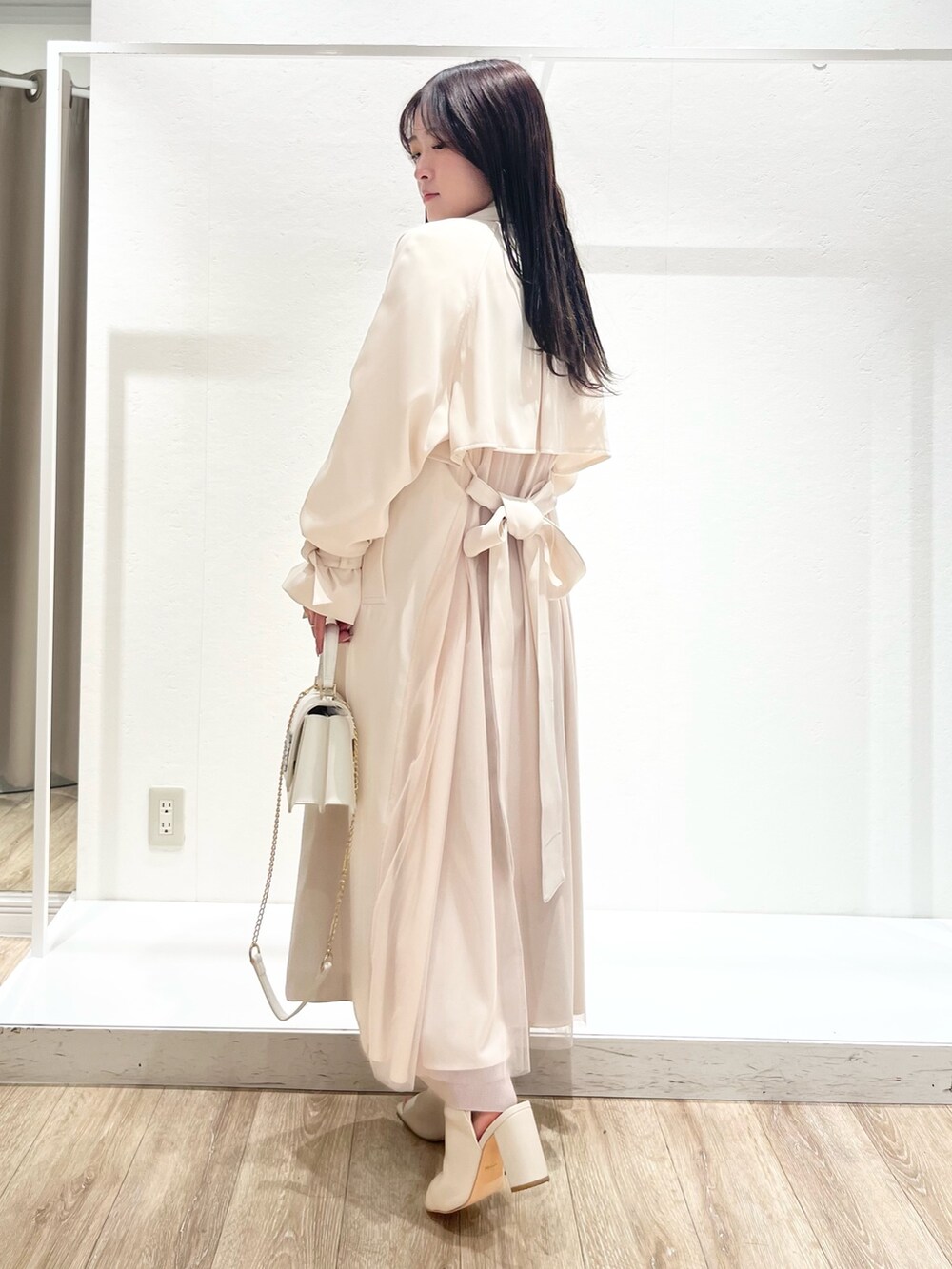 ホワイト系のトレンチコート、ベージュ系のワンピース、ホワイト系のショルダーバッグを着用したレディースの春コーディネートの3枚目の写真