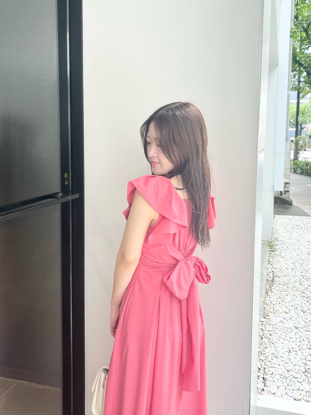 ピンク系のワンピース、ホワイト系のハンドバッグ、ホワイト系のパンプスを着用したレディースの夏コーディネートの7枚目の写真