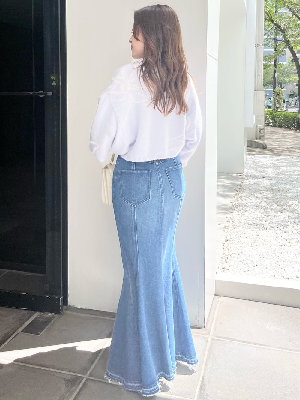 ブルー系のニット/セーター、ブルー系のデニムスカート、ベージュ系のブーツを着用したレディースの秋コーディネートの3枚目の写真