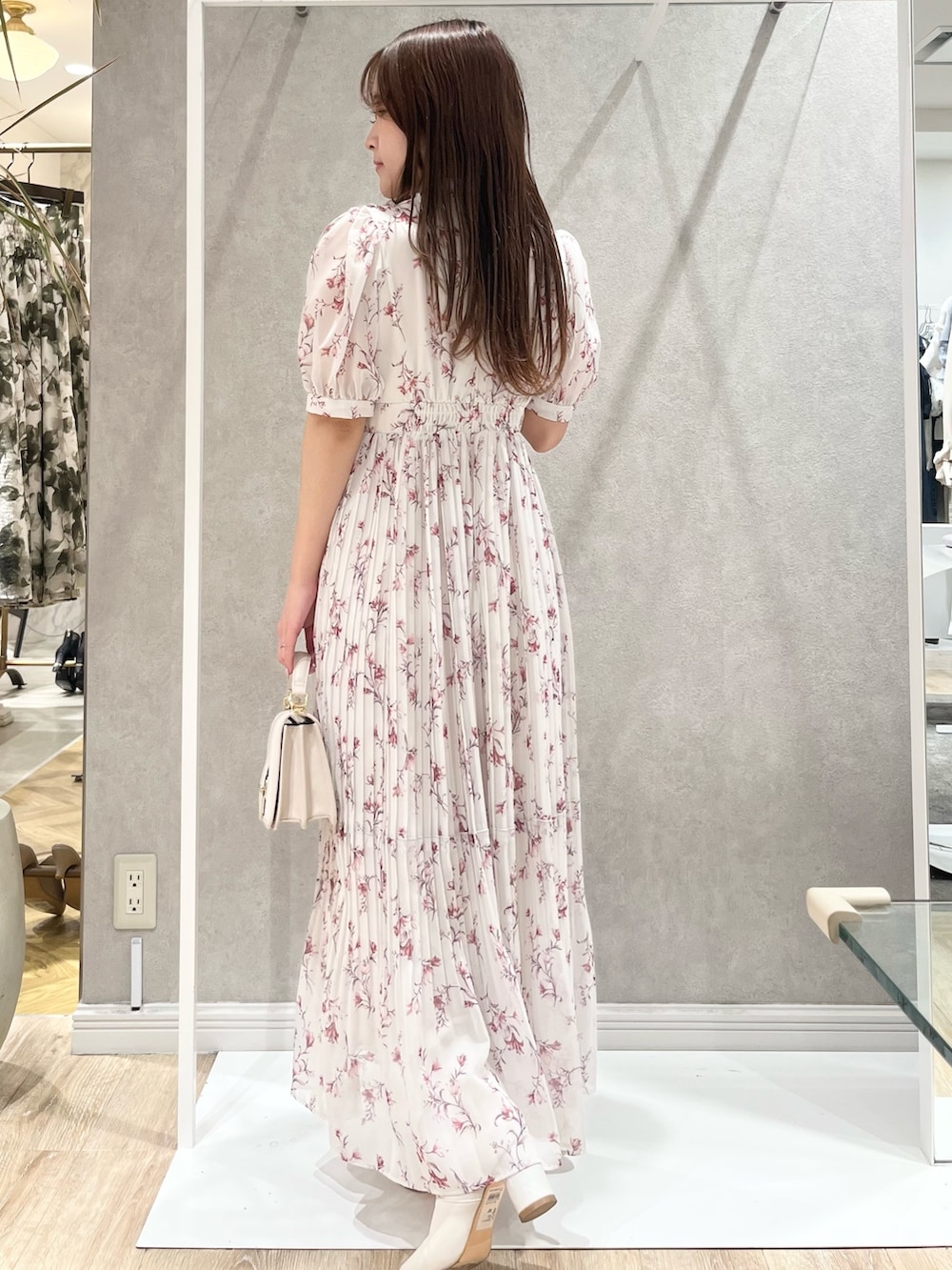 ホワイト系のトレンチコート、レッド系のワンピース、ホワイト系のハンドバッグを着用したレディースの春コーディネートの3枚目の写真