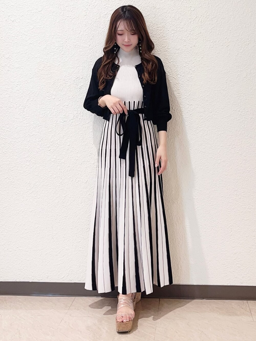 ホワイト系のワンピース、ブラック系のカーディガン/ボレロ、その他のサンダルを着用したレディースの春コーディネートの3枚目の写真