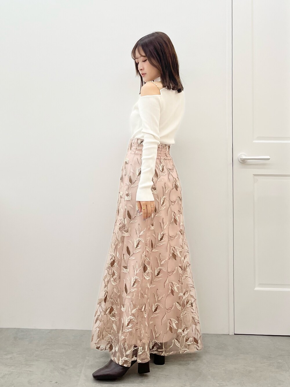 ピンク系のスカート、ホワイト系のニット/セーター、ホワイト系のその他アウターを着用したレディースの秋コーディネートの4枚目の写真