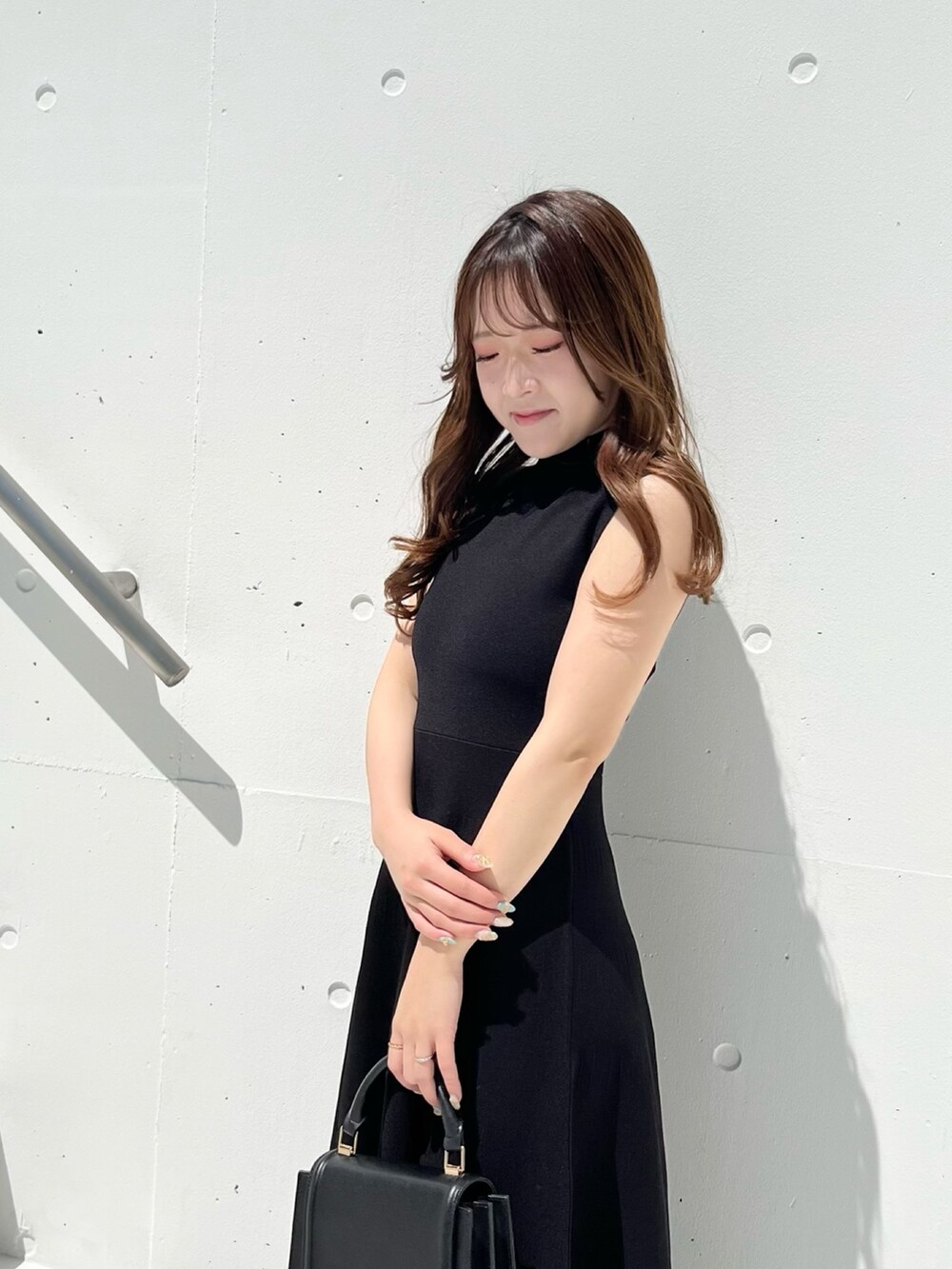 ブラック系のワンピース、ブラウン系のサンダル、ブラック系のハンドバッグを着用したレディースの春コーディネートの3枚目の写真