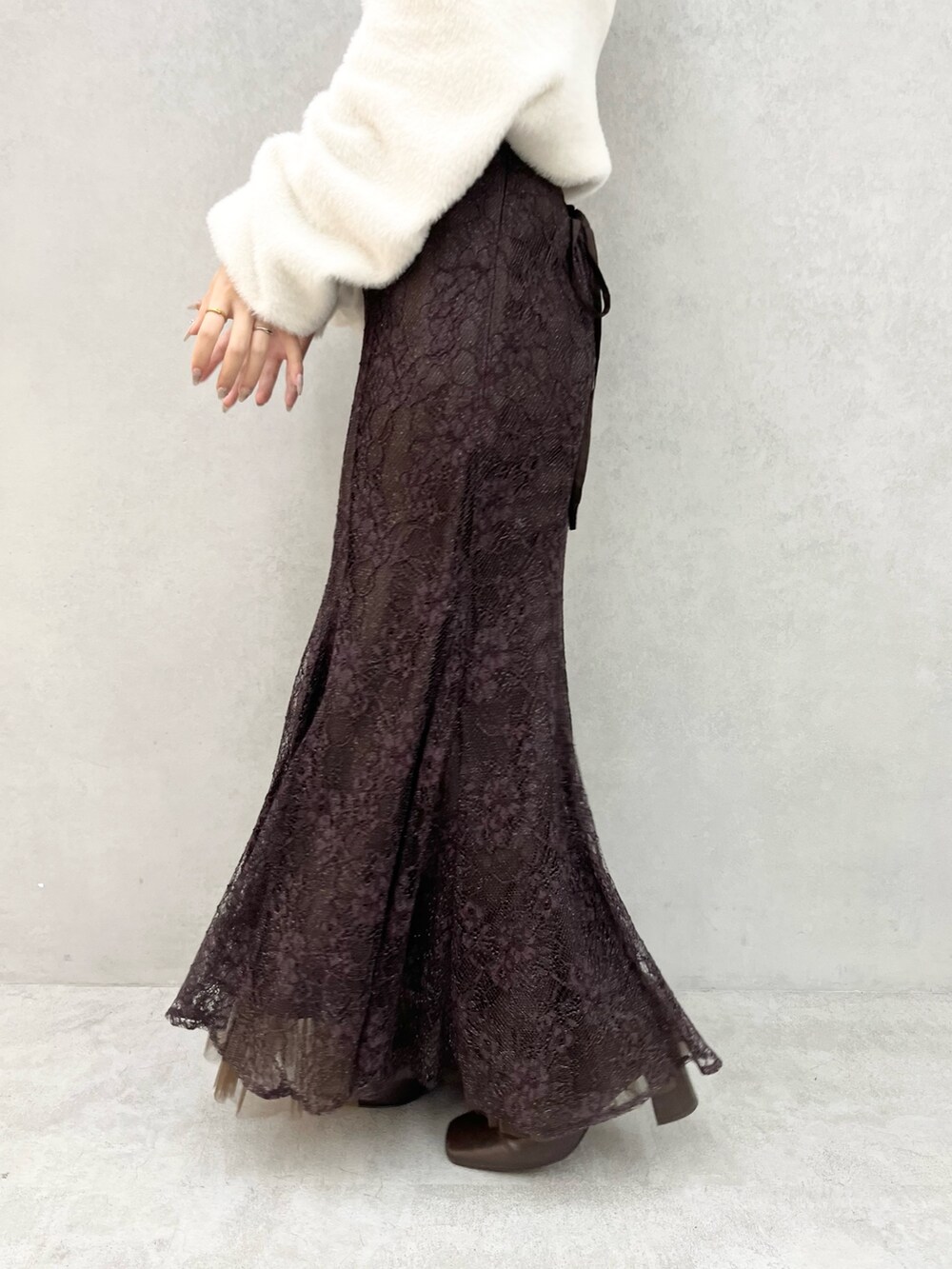 ホワイト系のニット/セーター、ブラウン系のスカート、ブラック系のブーツを着用したレディースの秋コーディネートの6枚目の写真