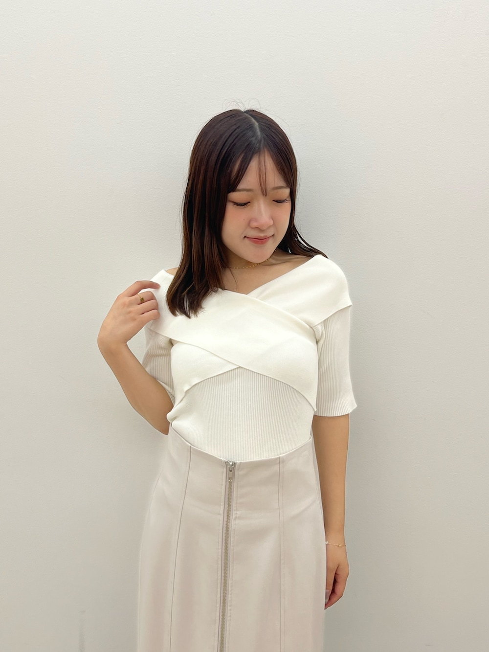 ホワイト系のニット/セーター、グレー系のスカートを着用したレディースの夏コーディネートの4枚目の写真