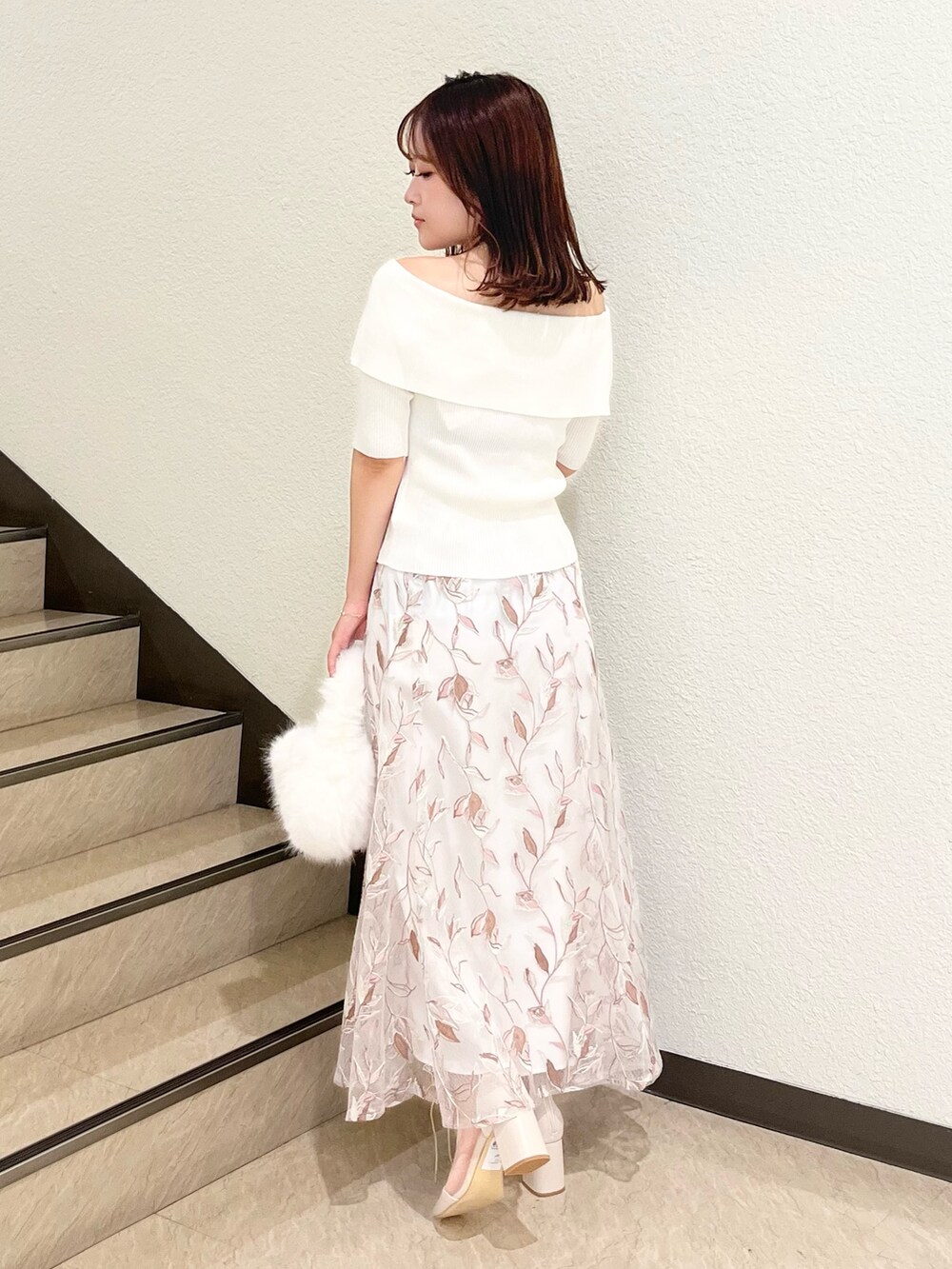 ホワイト系のニット/セーター、ホワイト系のスカート、ホワイト系のハンドバッグを着用したレディースの秋コーディネートの3枚目の写真