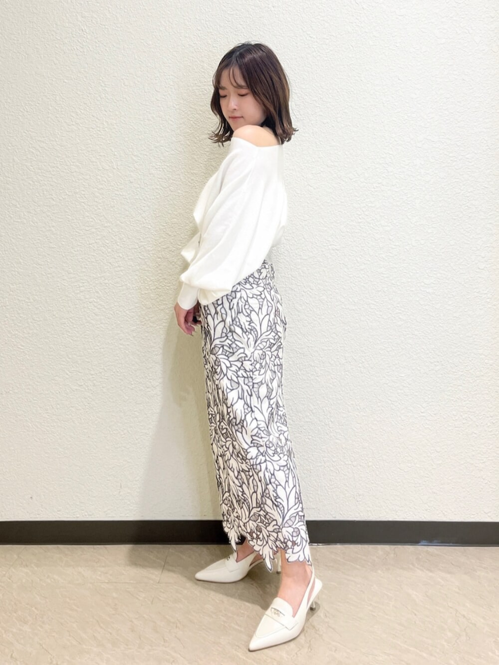 イエロー系のトレンチコート、ホワイト系のニット/セーター、ホワイト系のスカートを着用したレディースの冬コーディネートの5枚目の写真