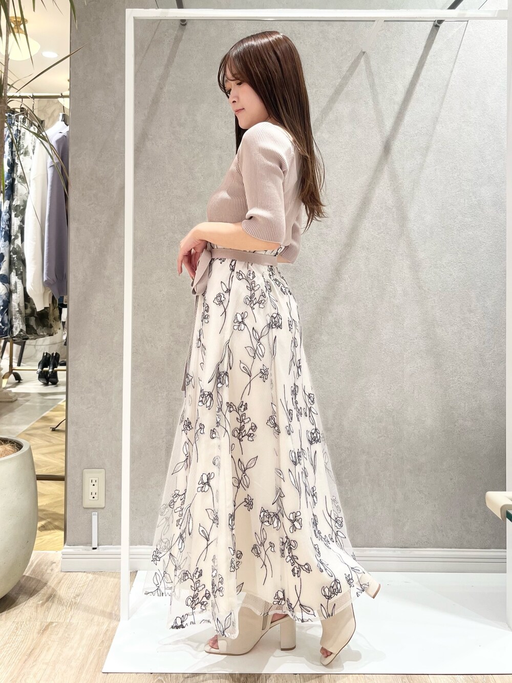 ベージュ系のワンピース、ホワイト系のライダースジャケット、ホワイト系のブーツを着用したレディースの春コーディネートの6枚目の写真