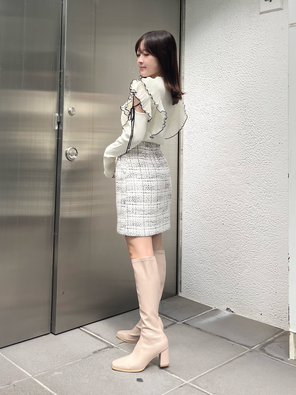 ホワイト系のニット/セーター、ホワイト系のスカート、ベージュ系のブーツを着用したレディースの秋コーディネートの2枚目の写真