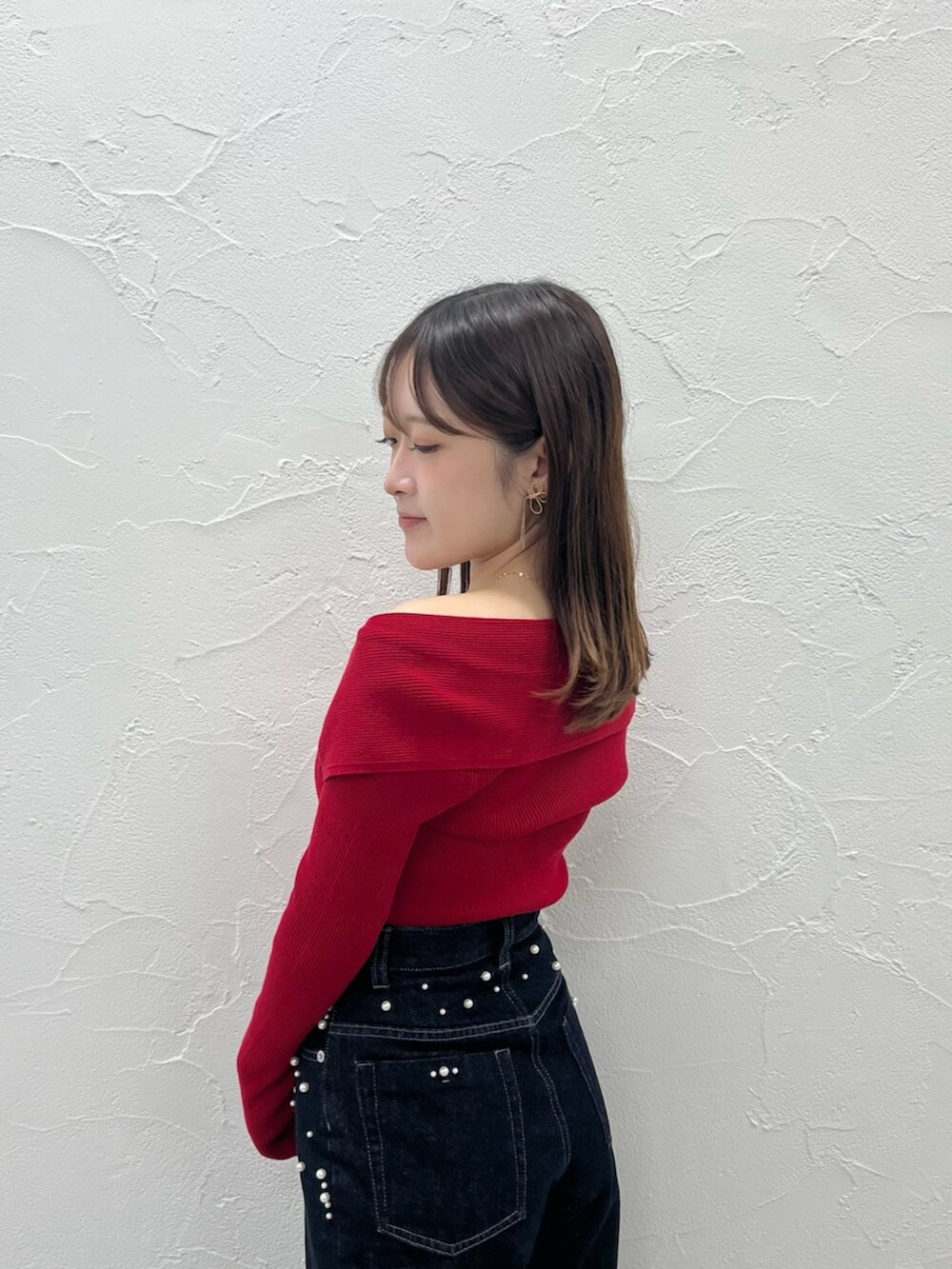 レッド系のニット/セーター、ブルー系のデニムパンツを着用したレディースの秋コーディネートの5枚目の写真