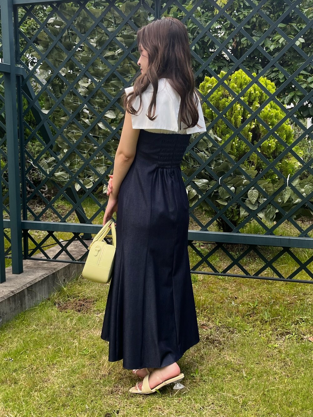 ブルー系のワンピース、イエロー系のボストンバッグ、イエロー系のサンダルを着用したレディースの夏コーディネートの7枚目の写真