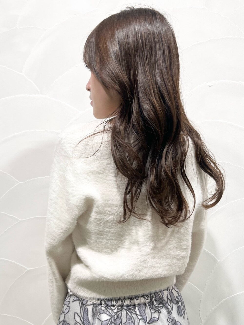 ホワイト系のカーディガン/ボレロ、グレー系のスカート、ブラック系のブーツを着用したレディースの冬コーディネートの7枚目の写真