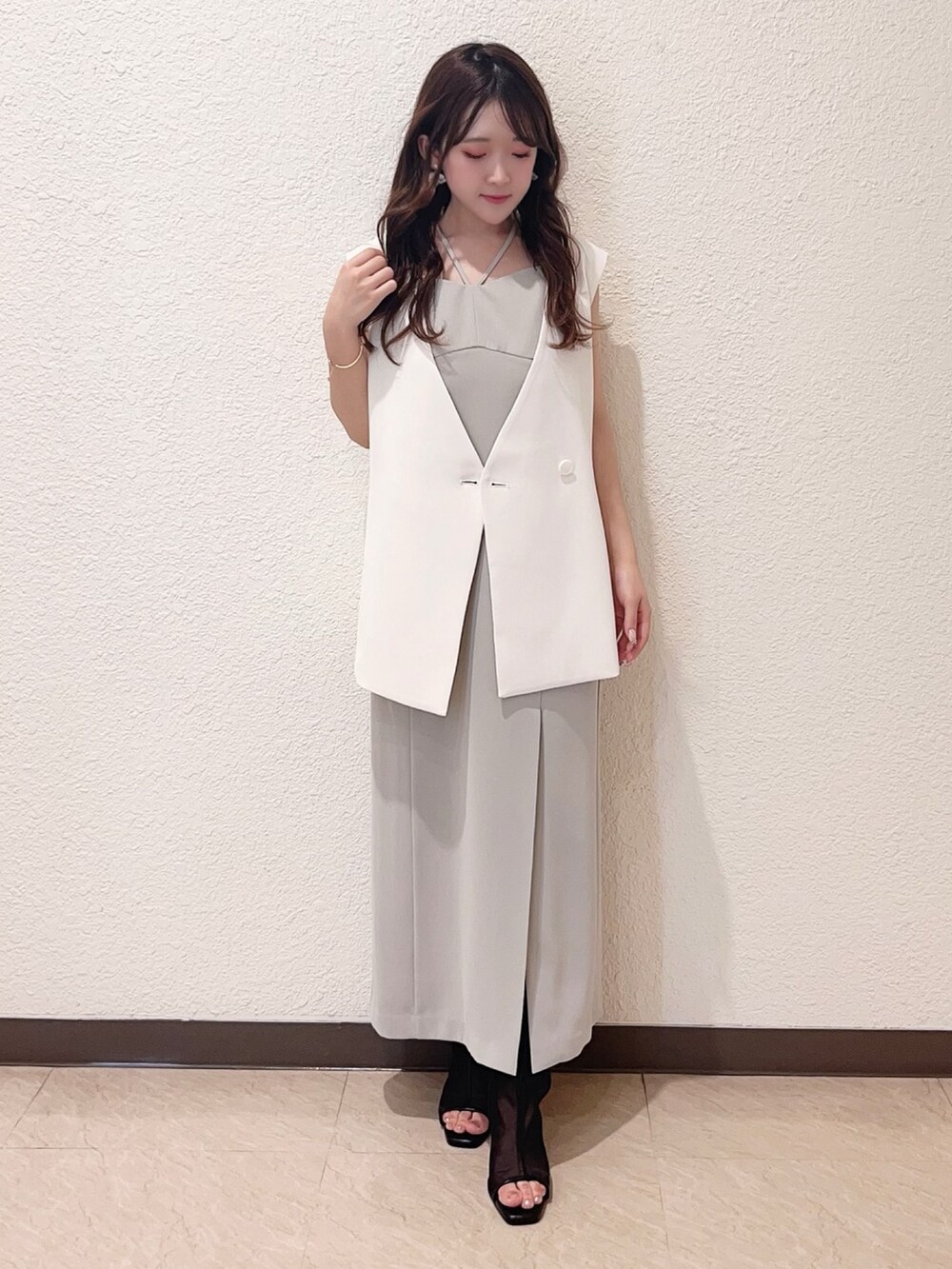 グリーン系のワンピース、ホワイト系のベスト、ブラック系のハンドバッグを着用したレディースの春コーディネートの3枚目の写真