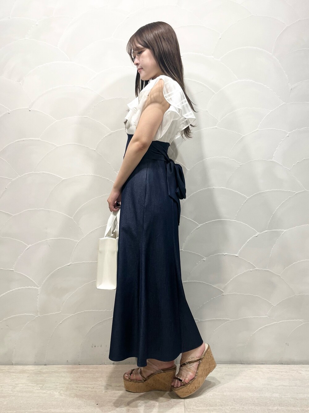 ホワイト系のワンピース、ホワイト系のトートバッグ、ブラウン系のサンダルを着用したレディースの春コーディネートの2枚目の写真