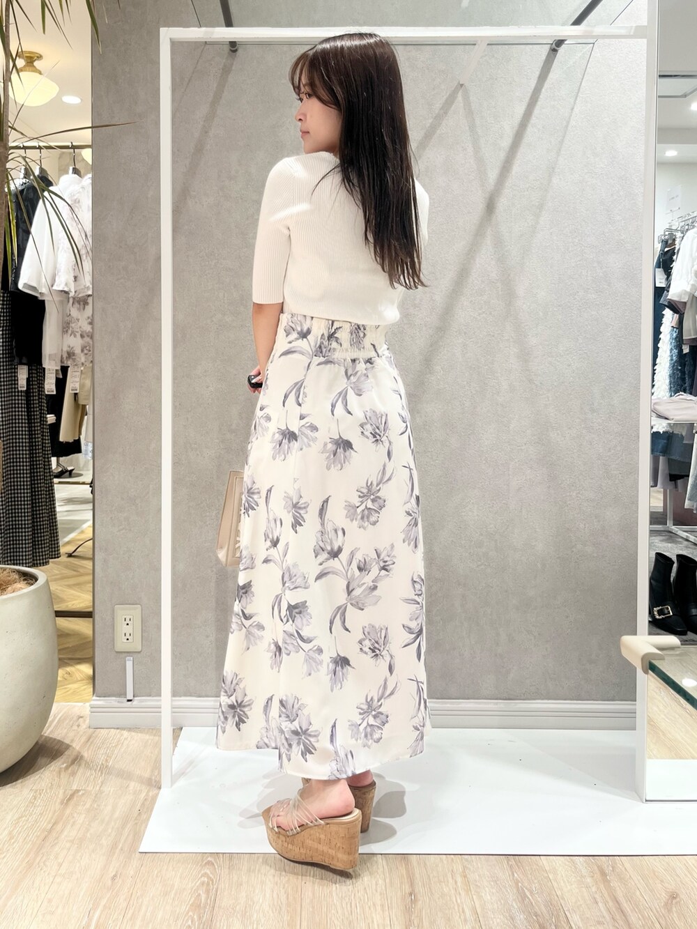 ホワイト系のニット/セーター、グレー系のスカート、ベージュ系のショルダーバッグを着用したレディースの春コーディネートの3枚目の写真