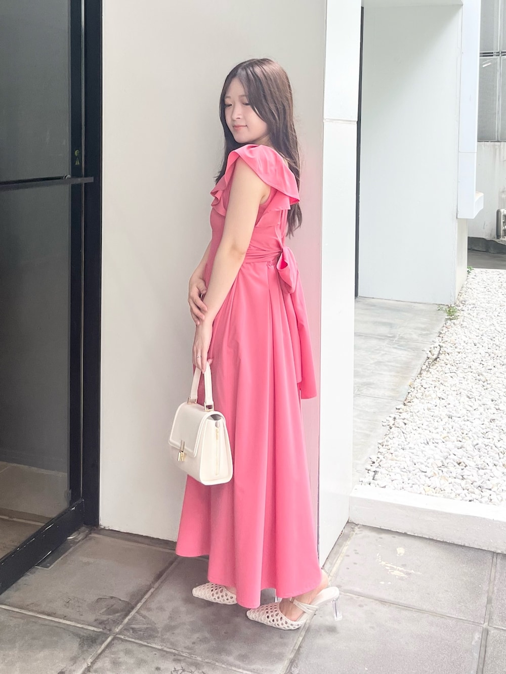 ピンク系のワンピース、ホワイト系のハンドバッグ、ホワイト系のパンプスを着用したレディースの夏コーディネートの2枚目の写真