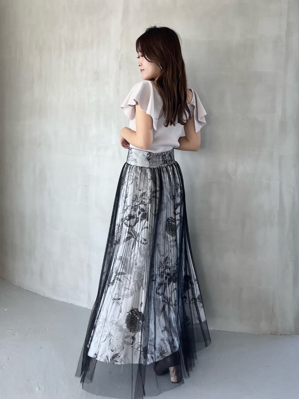 ブラック系のスカート、ピンク系のニット/セーター、ブラウン系のブーツを着用したレディースの春コーディネートの3枚目の写真