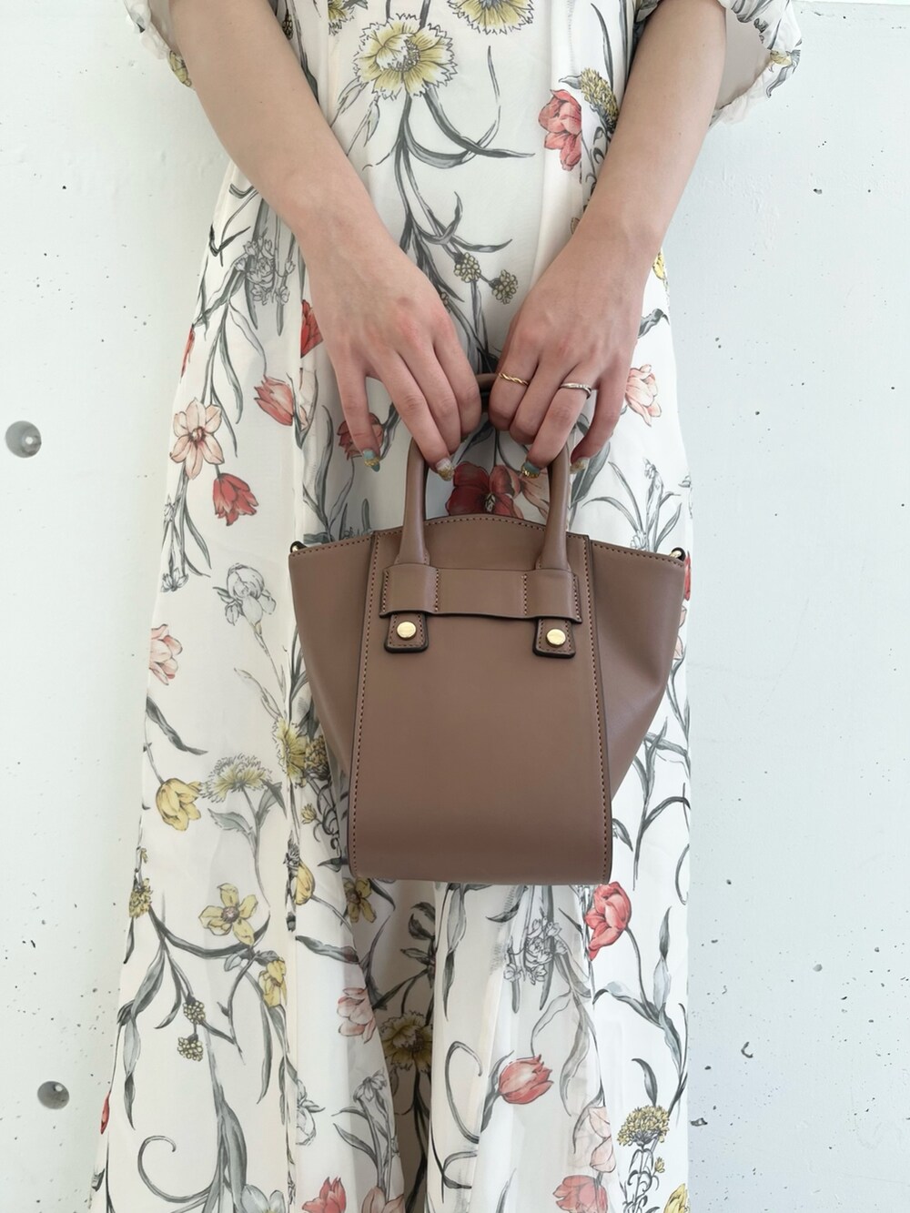 ホワイト系のワンピース、ブラウン系のハンドバッグ、ブラウン系のブーツを着用したレディースの夏コーディネートの7枚目の写真