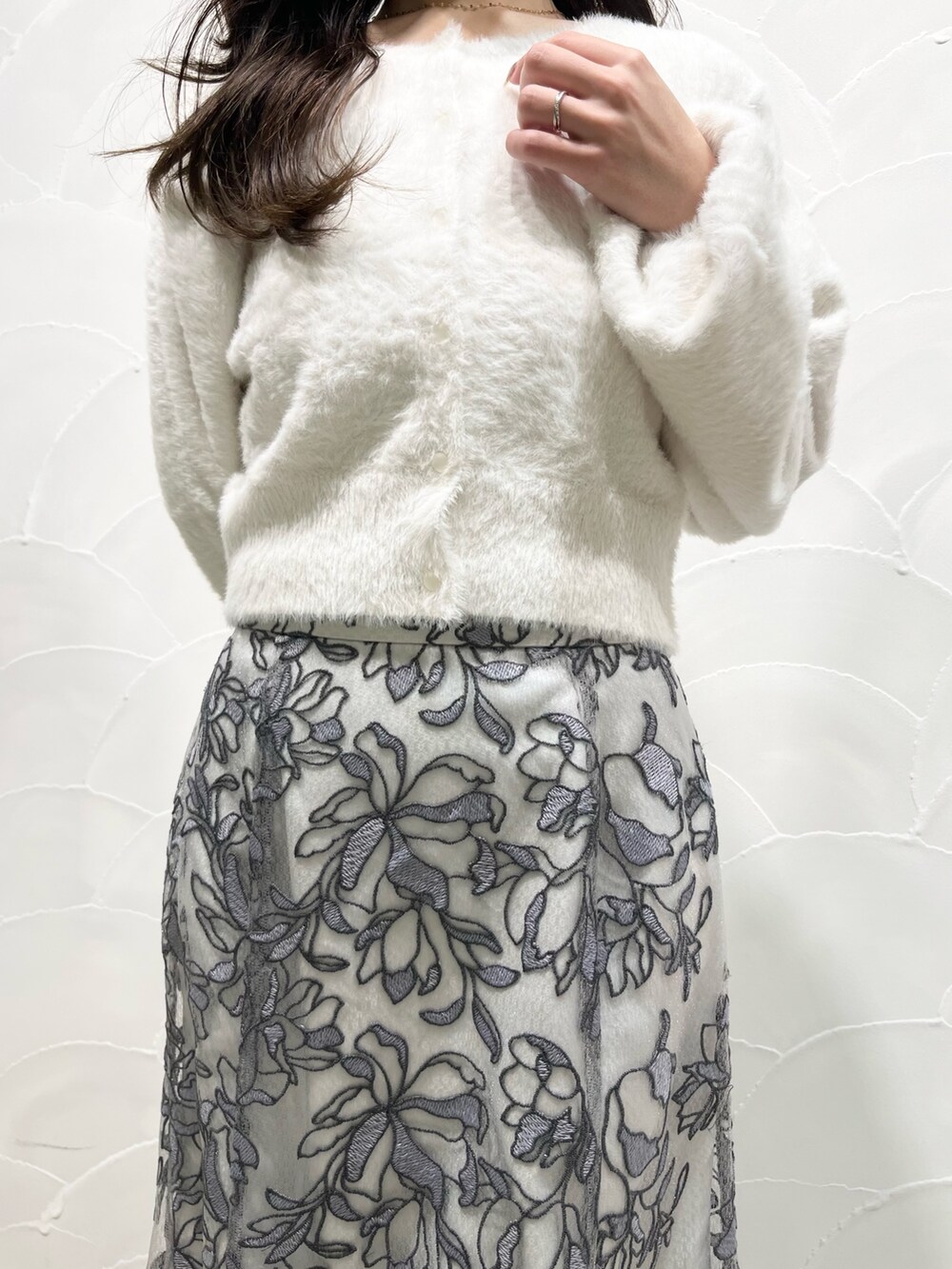 ホワイト系のカーディガン/ボレロ、グレー系のスカート、ブラック系のブーツを着用したレディースの冬コーディネートの4枚目の写真