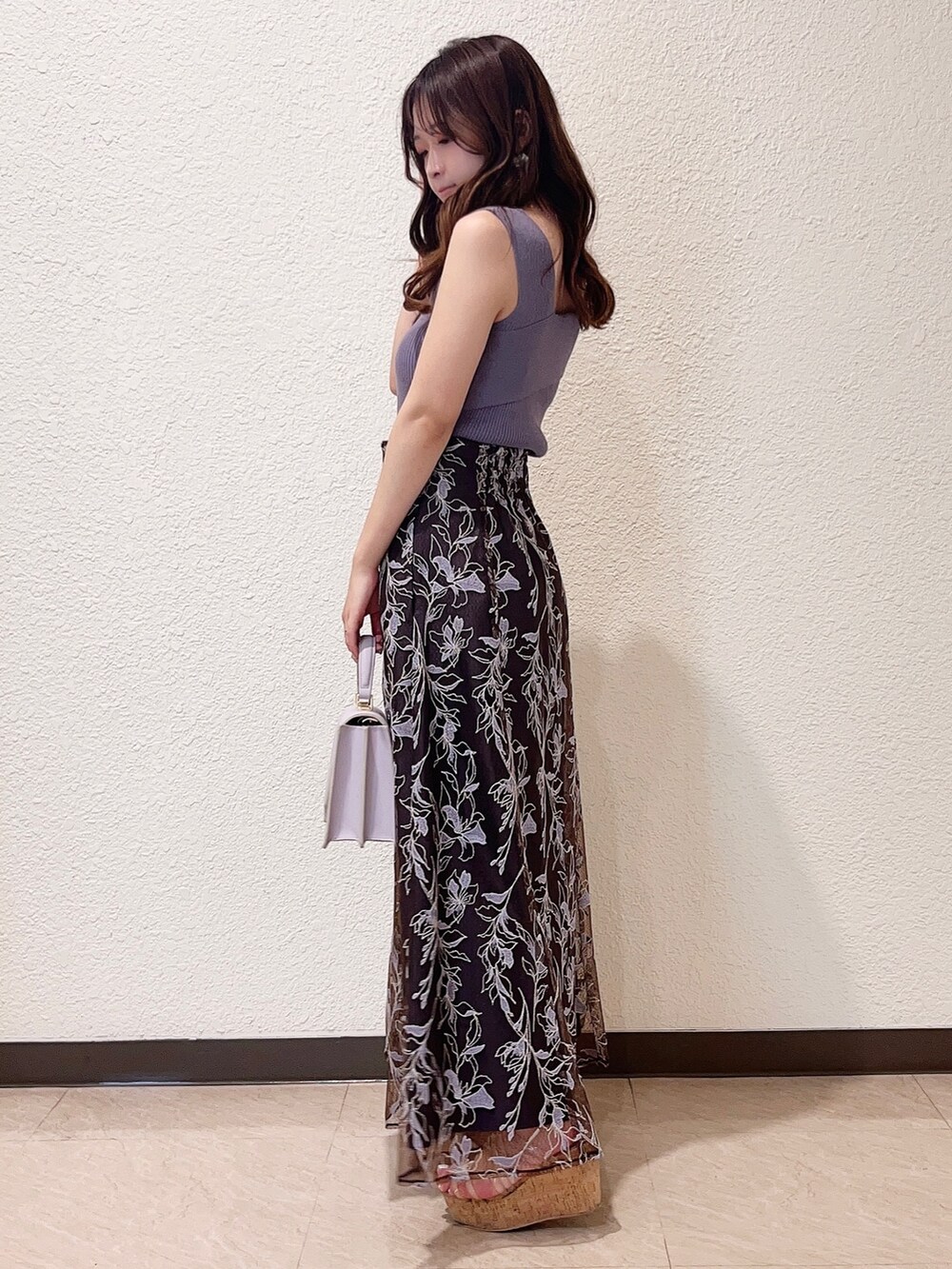 パープル系のスカート、パープル系のニット/セーター、パープル系のハンドバッグを着用したレディースの春コーディネートの2枚目の写真