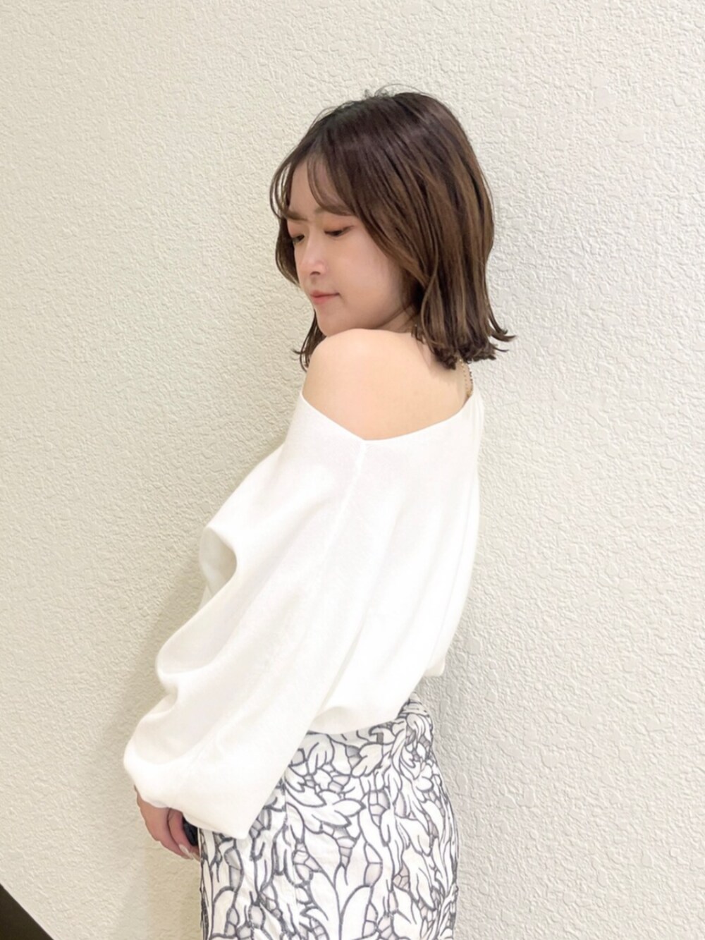 イエロー系のトレンチコート、ホワイト系のニット/セーター、ホワイト系のスカートを着用したレディースの冬コーディネートの7枚目の写真