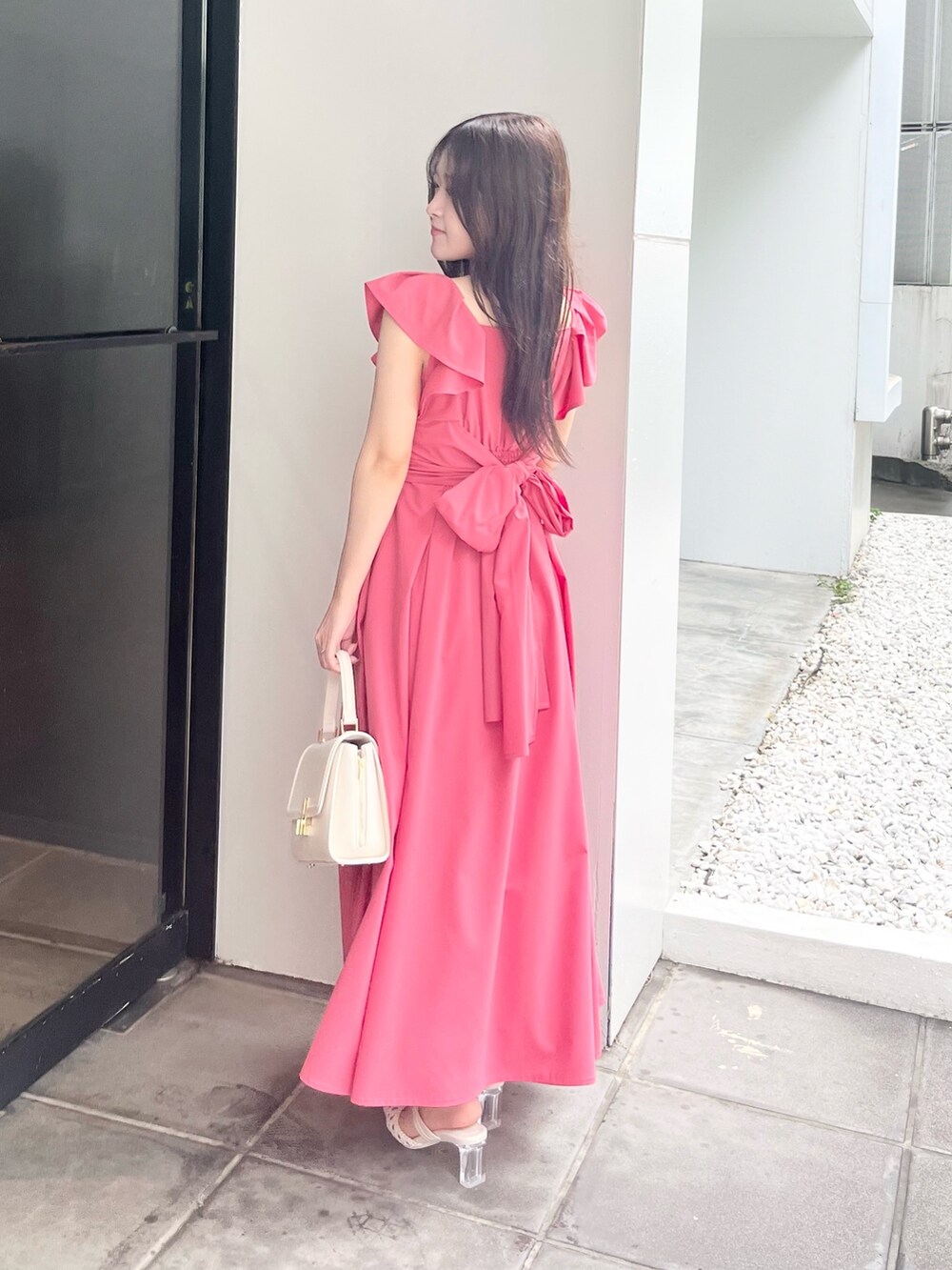 ピンク系のワンピース、ホワイト系のハンドバッグ、ホワイト系のパンプスを着用したレディースの夏コーディネートの3枚目の写真