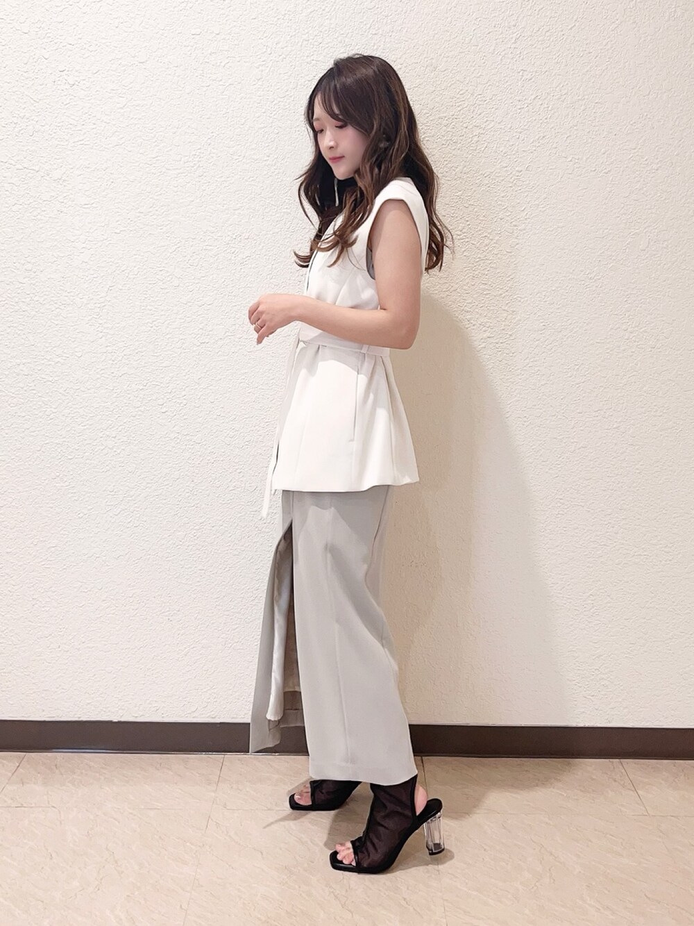 グリーン系のワンピース、ホワイト系のベスト、ブラック系のハンドバッグを着用したレディースの春コーディネートの2枚目の写真