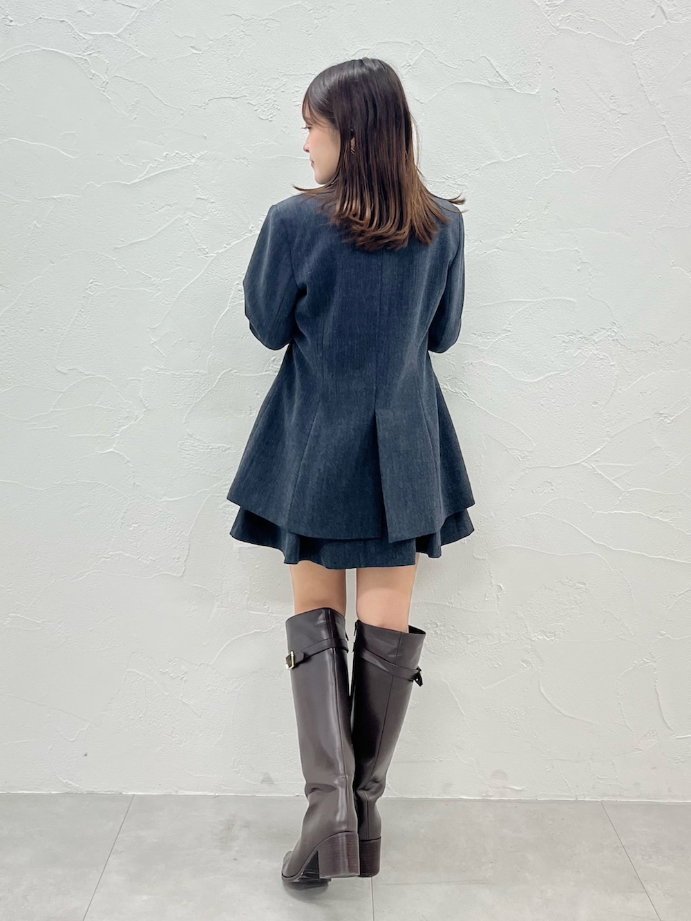 グレー系のニット/セーター、グレー系のテーラードジャケット、グレー系のスカートを着用したレディースの秋コーディネートの2枚目の写真