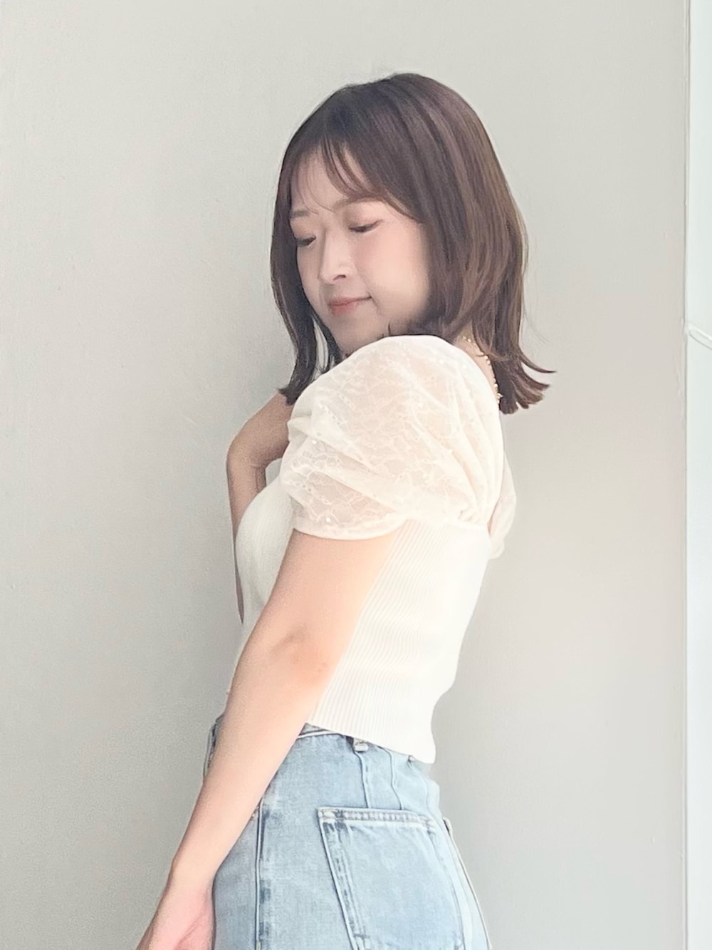 ホワイト系のニット/セーター、ブルー系のデニムパンツ、ホワイト系のトートバッグを着用したレディースの夏コーディネートの7枚目の写真