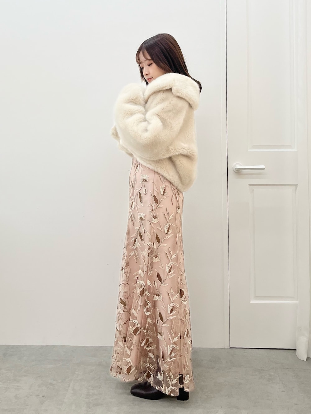 ピンク系のスカート、ホワイト系のニット/セーター、ホワイト系のその他アウターを着用したレディースの秋コーディネートの2枚目の写真