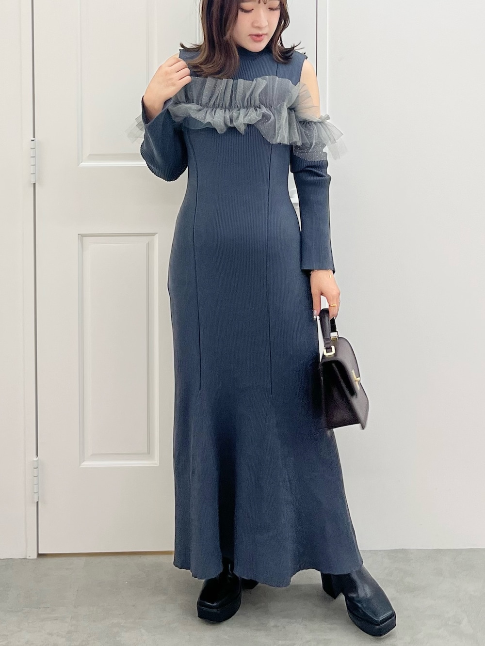 グレー系のワンピース、ブラウン系のハンドバッグ、ブラック系のブーツを着用したレディースの秋コーディネートの6枚目の写真