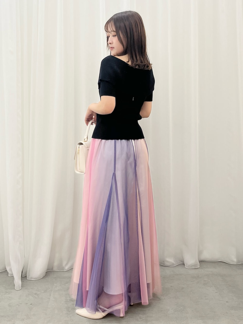 ブラック系のニット/セーター、パープル系のスカート、ベージュ系のパンプスを着用したレディースの夏コーディネートの2枚目の写真