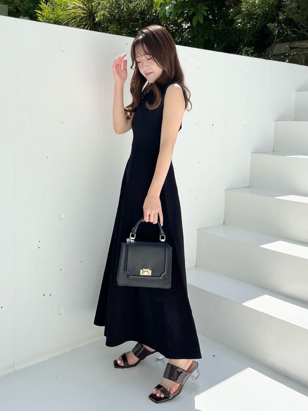 ブラック系のワンピース、ブラウン系のサンダル、ブラック系のハンドバッグを着用したレディースの春コーディネートの2枚目の写真