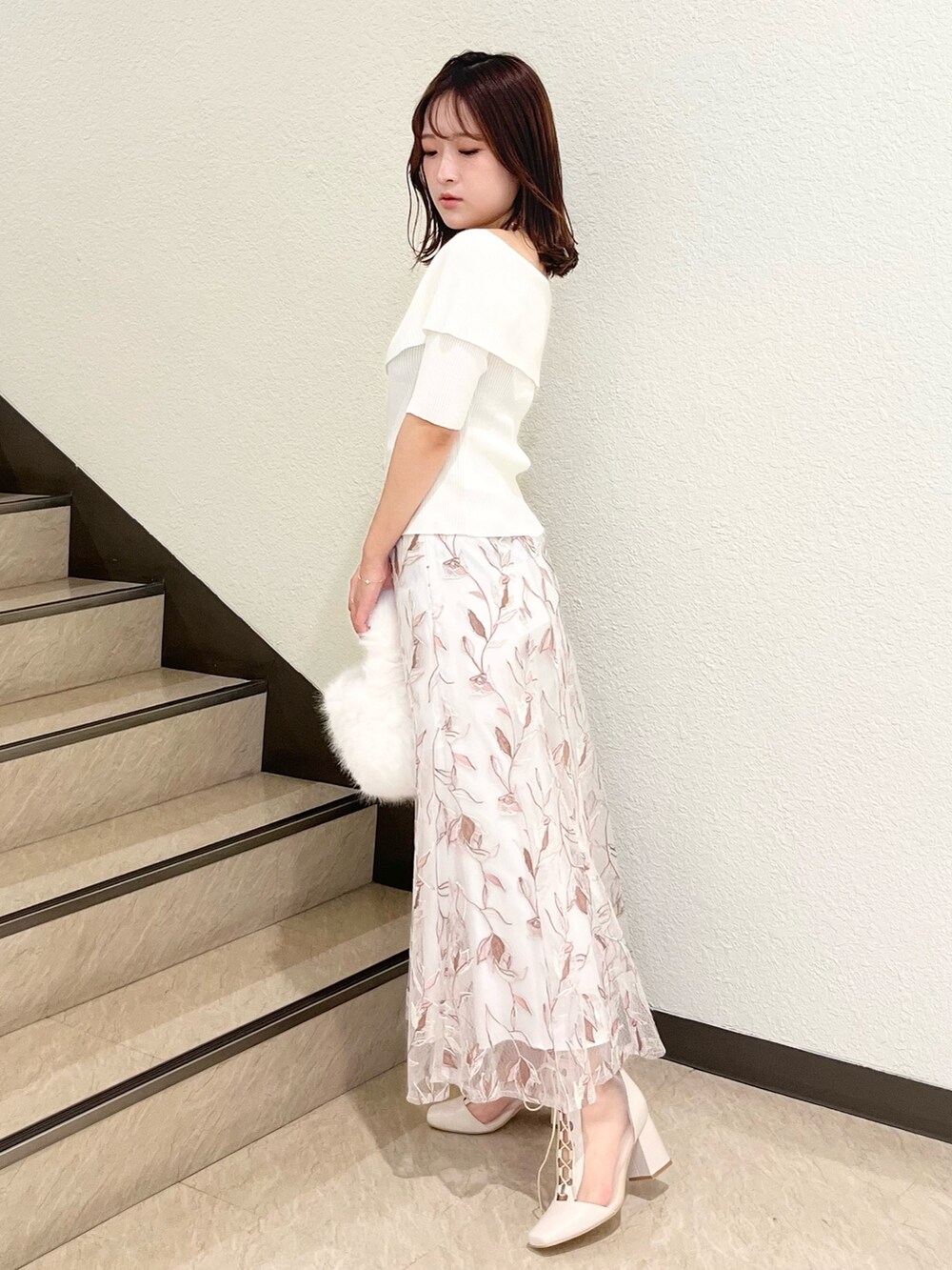 ホワイト系のニット/セーター、ホワイト系のスカート、ホワイト系のハンドバッグを着用したレディースの秋コーディネートの2枚目の写真