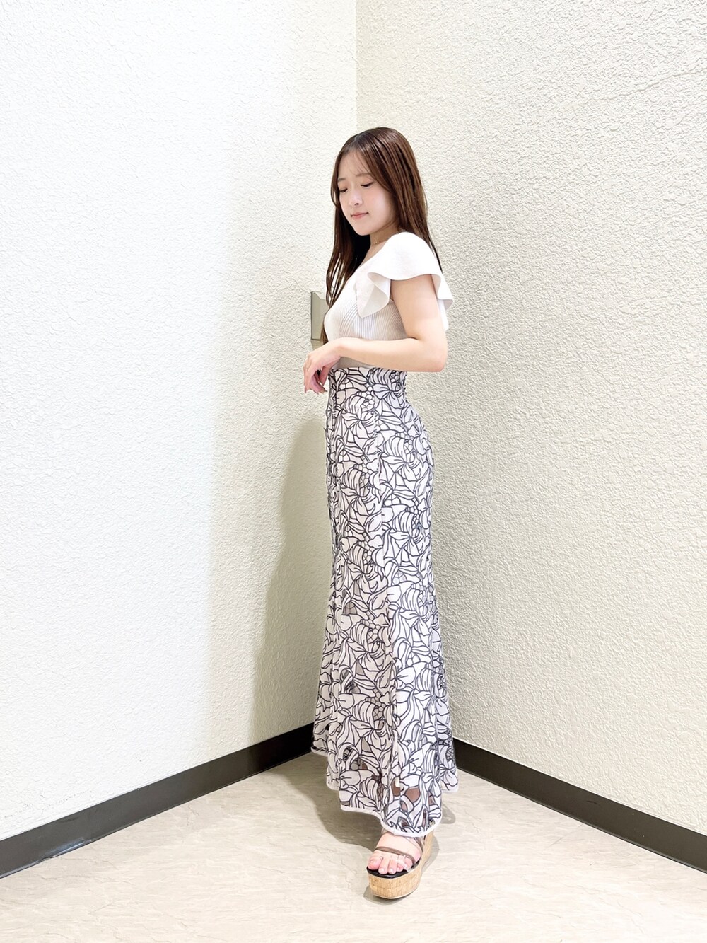 ピンク系のニット/セーター、ベージュ系のスカート、ブラック系のサンダルを着用したレディースの夏コーディネートの2枚目の写真