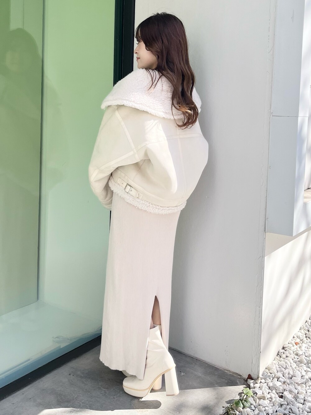 ホワイト系のムートンコート、ベージュ系のワンピース、ホワイト系のブーツを着用したレディースの秋コーディネートの2枚目の写真