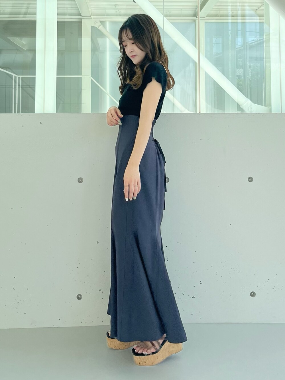 ブラック系のニット/セーター、グレー系のスカート、ブラック系のサンダルを着用したレディースの夏コーディネートの2枚目の写真